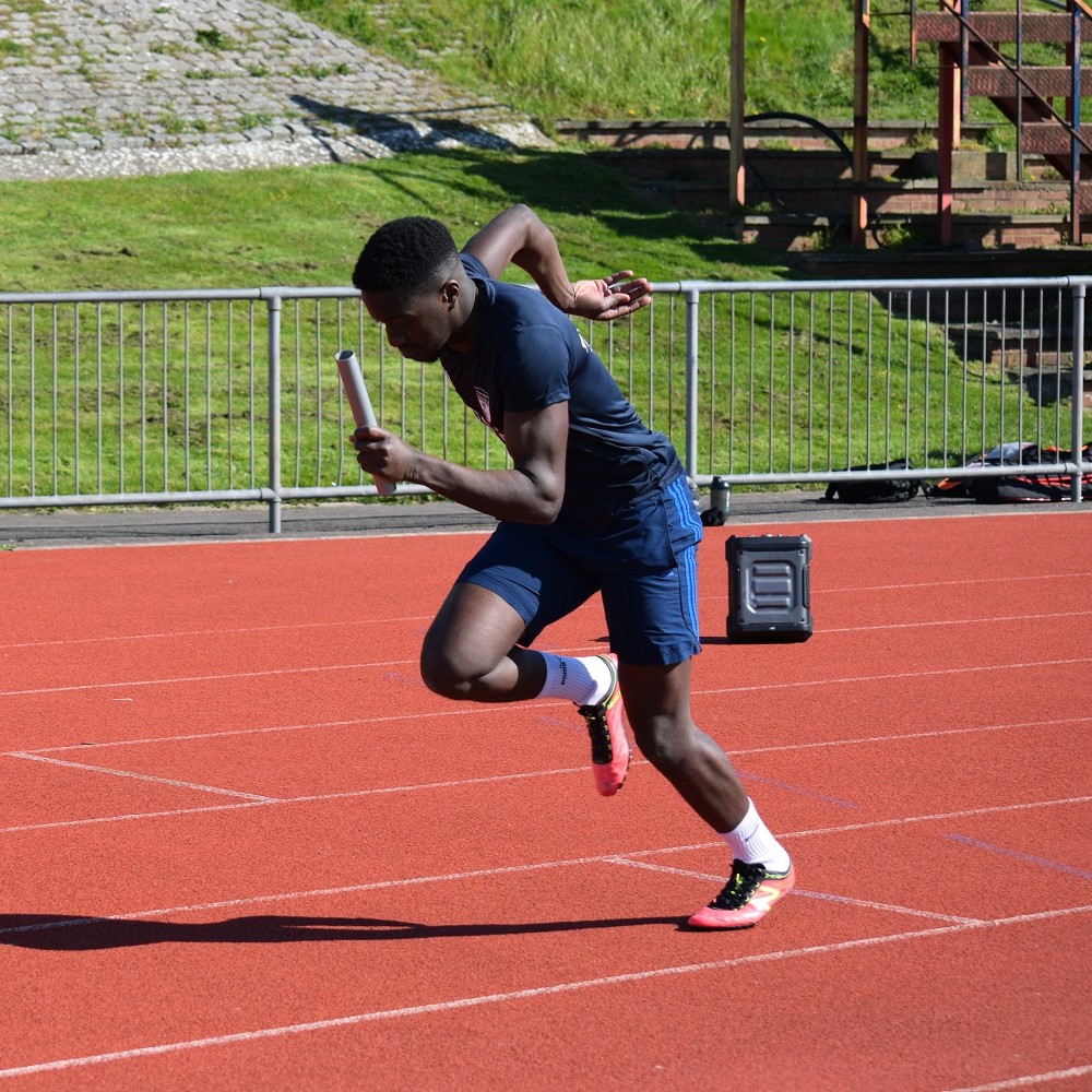 Photo of an Athletics member competing in a relay race at Varsity