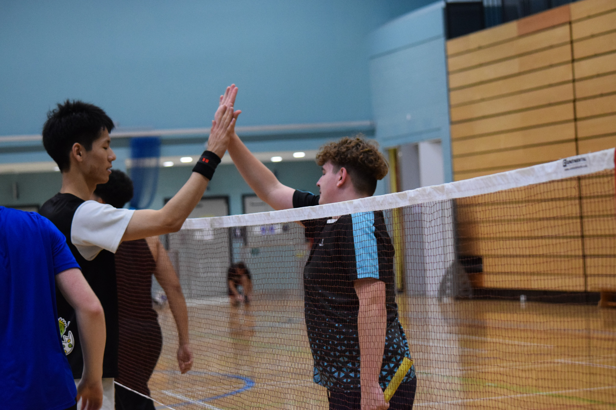 A photo of two badminton players hi-fiving over the net